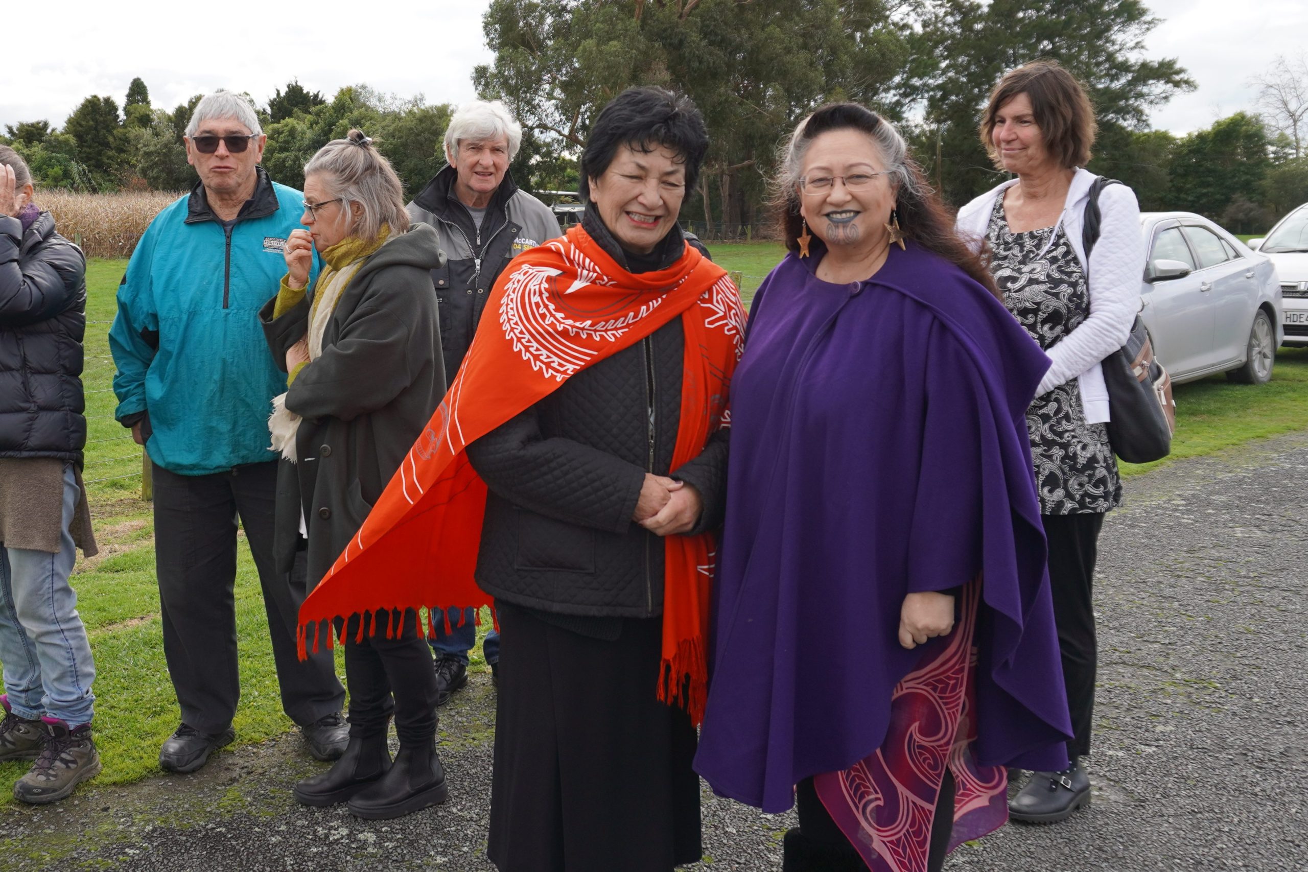 Aki Paipper and Elizabeth Kerekere stand on a footpath with other people in the background. They are smiling for the camera. 